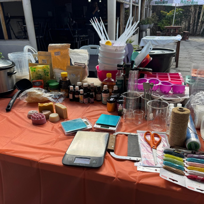 Table with various items including bottles, containers, and tools on an orange tablecloth.