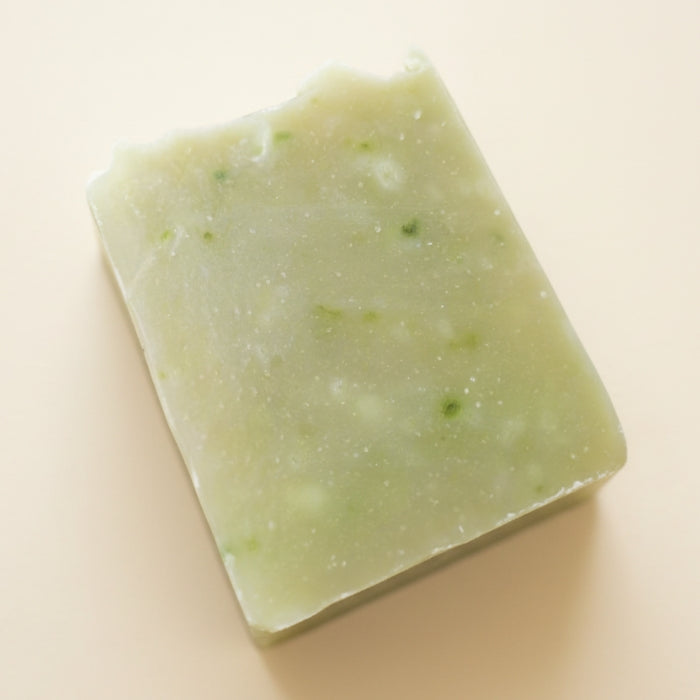 Green soap bar with specks on a beige background