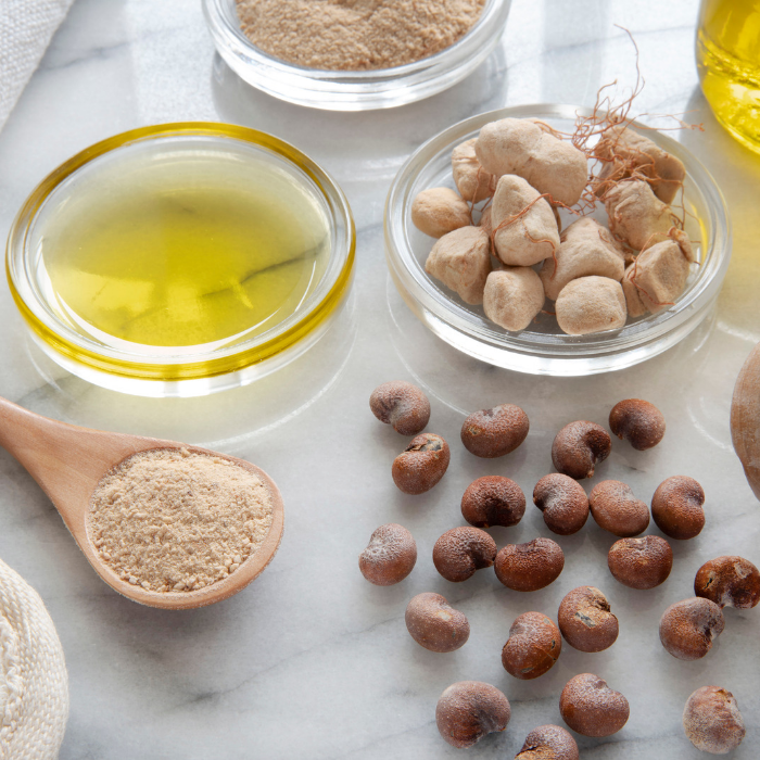 Baobab Nuts, oil, and a wooden spoon with a baobab powder on a marble surface