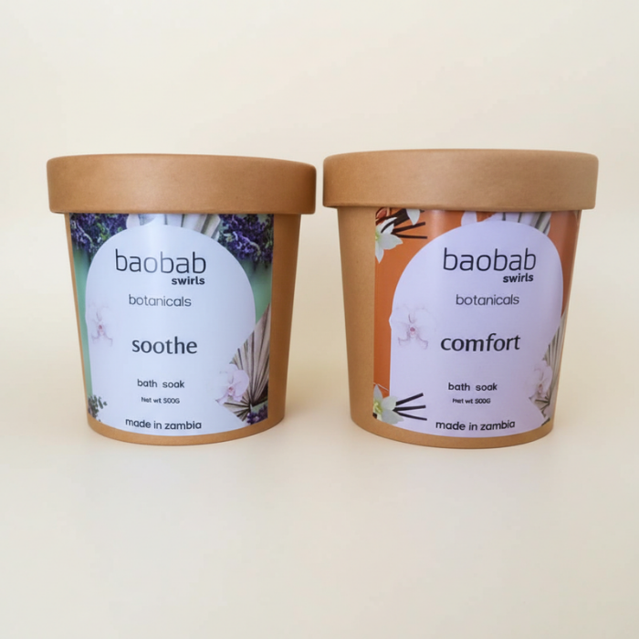 Two kraft paper tubs of babab swirls botanicals bath soaks, labeled 'soothe' and 'comfort', on a plain beige background.