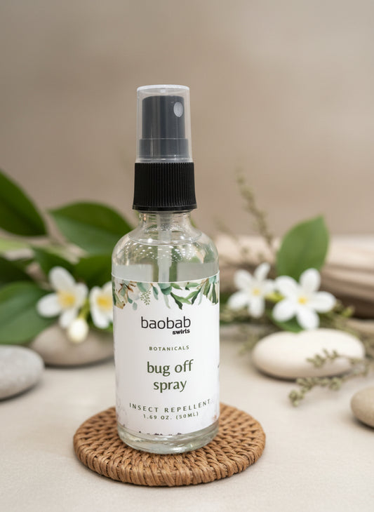 Bug off spray bottle by baobab on a woven coaster with flowers and stones in the background