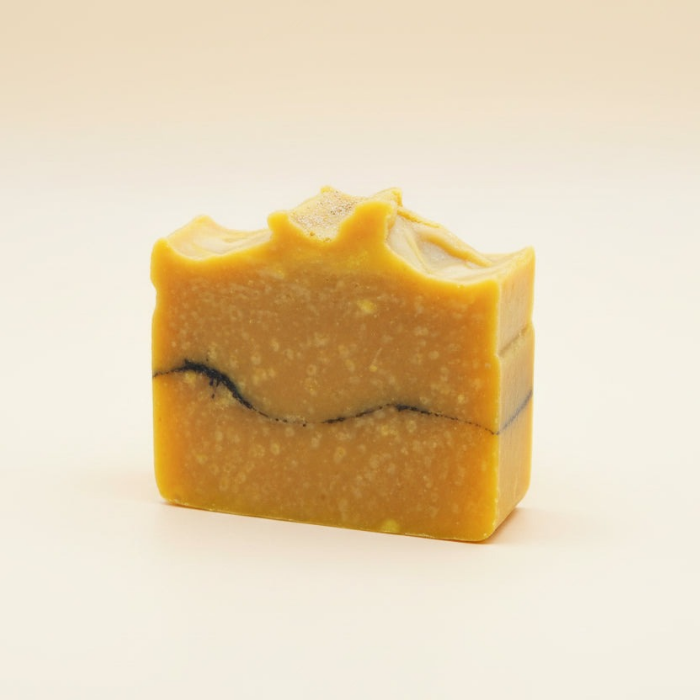 Yellow soap bar with black streaks on a beige background