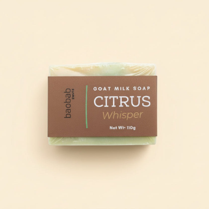 Bar of goat milk soap with 'Citrus Whisper' packaging on a beige background