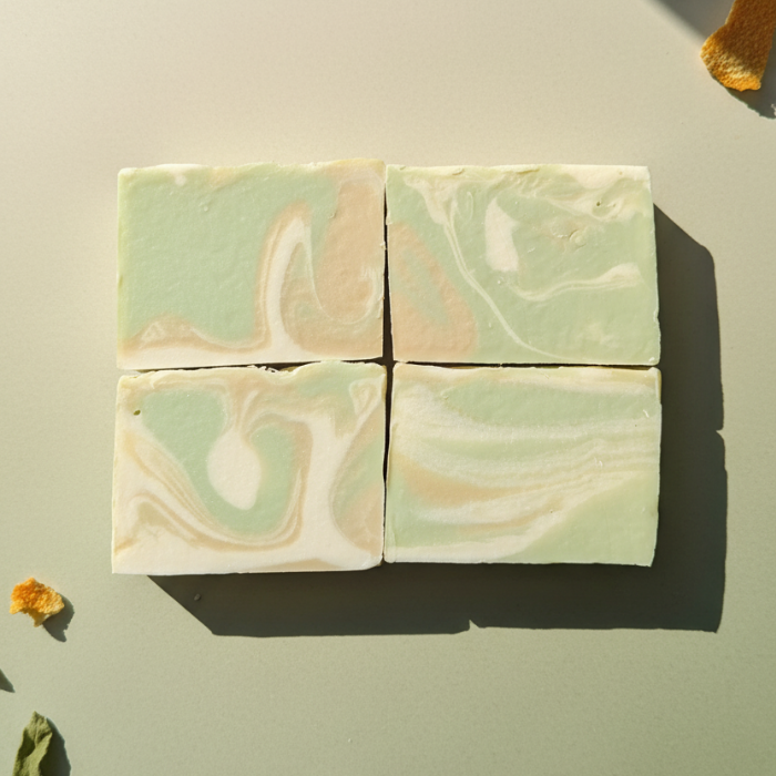Swirled green and beige soap bars on a light surface with dried flowers.