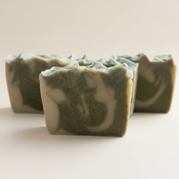 Three green and white soap bars on a light beige background