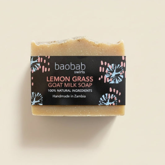 Baobab Swirls Bar of lemon grass goat milk soap with a dark brown label on a beige background
