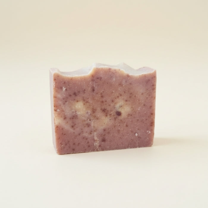 Bar of soap with visible ingredients on a plain background