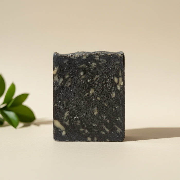 Bar of black soap with white specks on a beige background