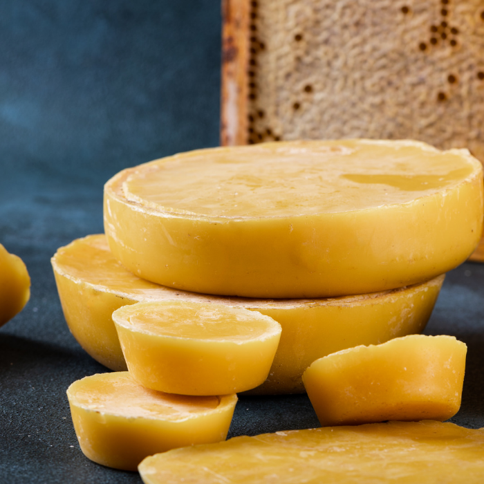 Yellow beeswax products on a dark surface with a wooden block in the background.