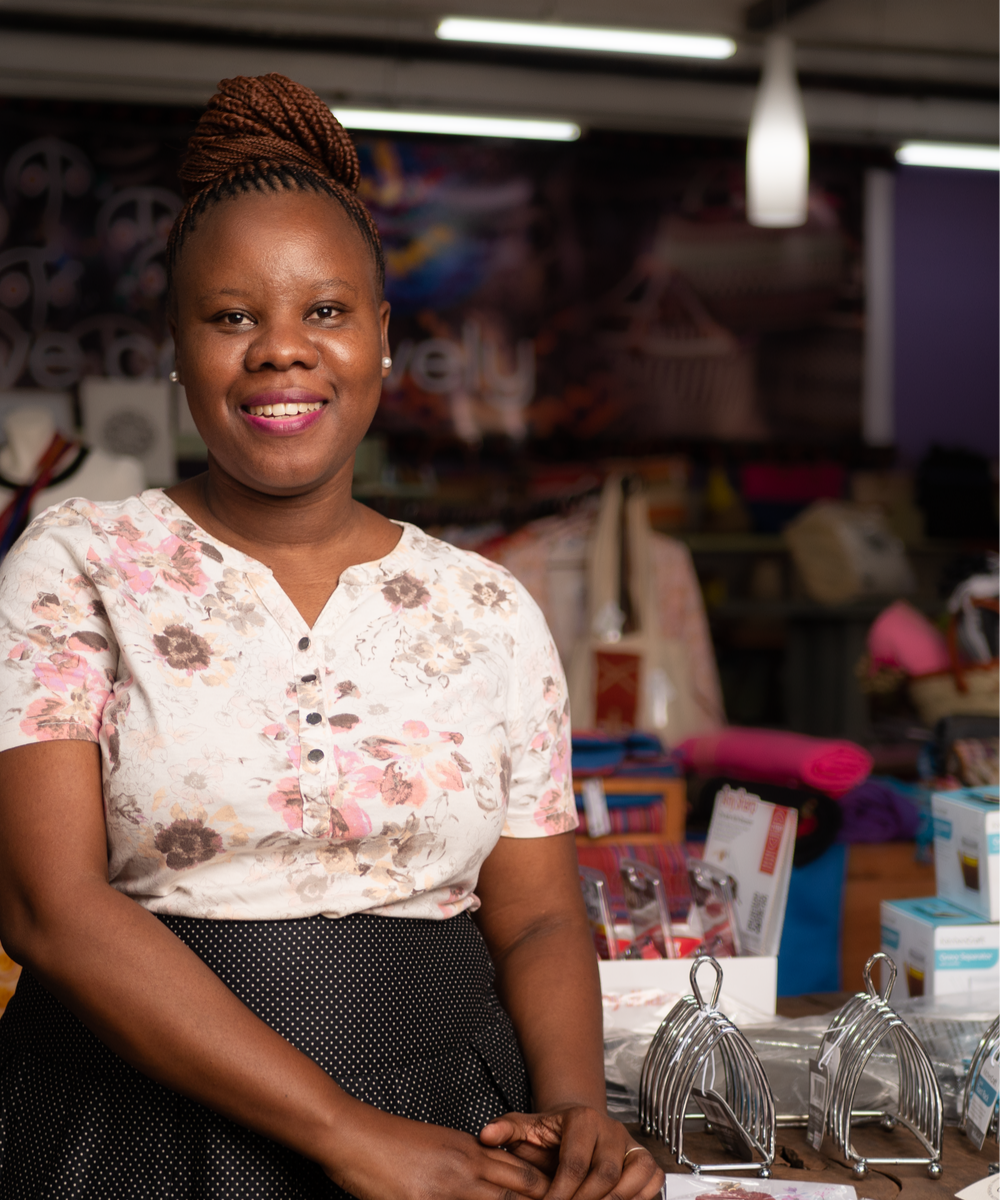 Rosalina ,founder of Baoban Swirls in a floral shirt sitting at a desk with a colorful background