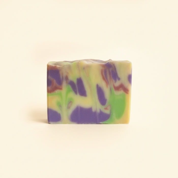 Colorful soap bar with purple and green swirls on a beige background