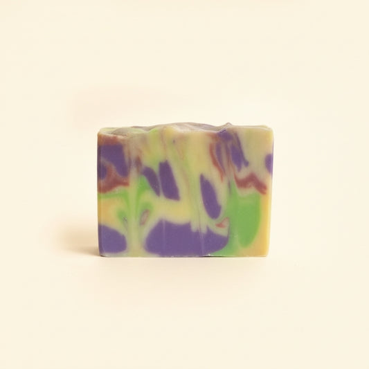 Colorful soap bar with purple and green swirls on a beige background