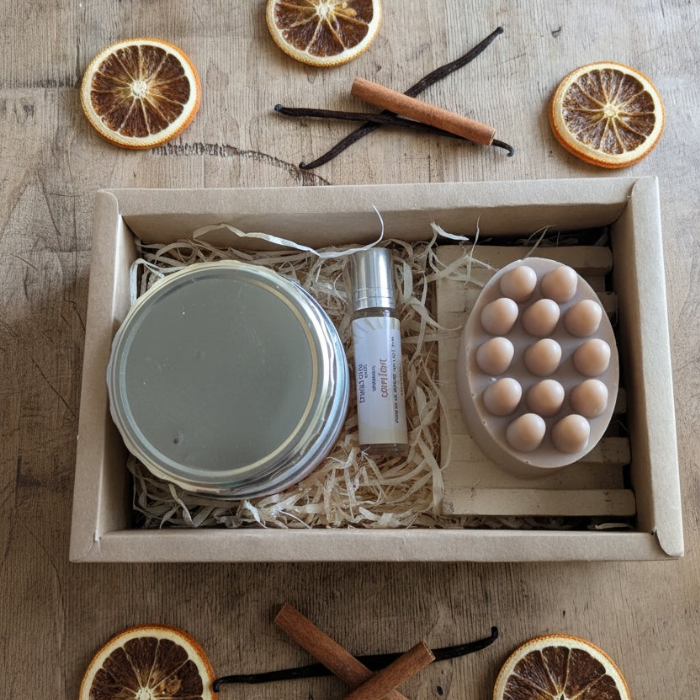 Box containing skincare products with dried oranges and vanilla beans on a wooden surface