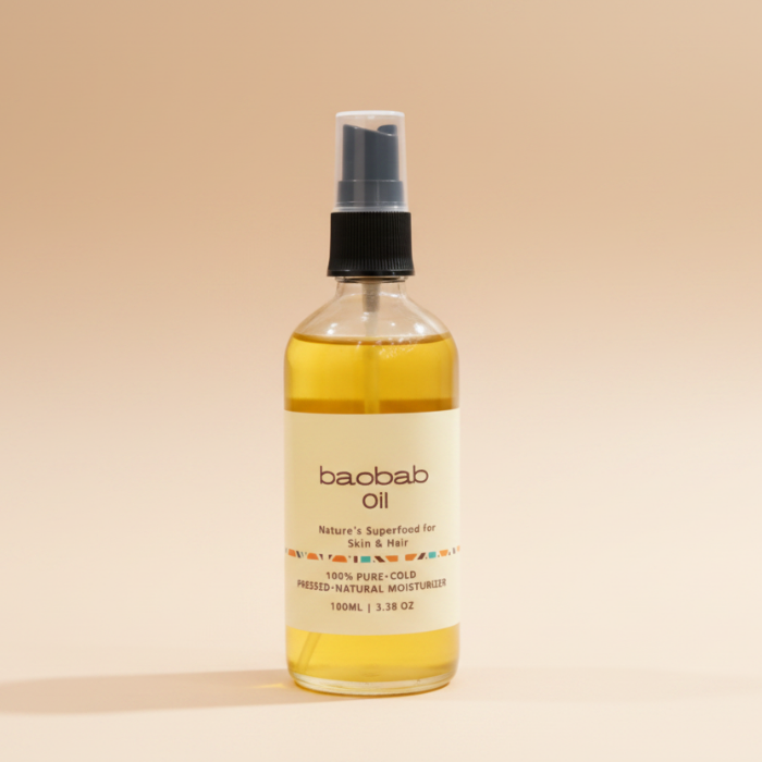 A 100mL bottle of baobab oil moisturizer with a black spray nozzle and a cream-colored label, set against a solid beige background.